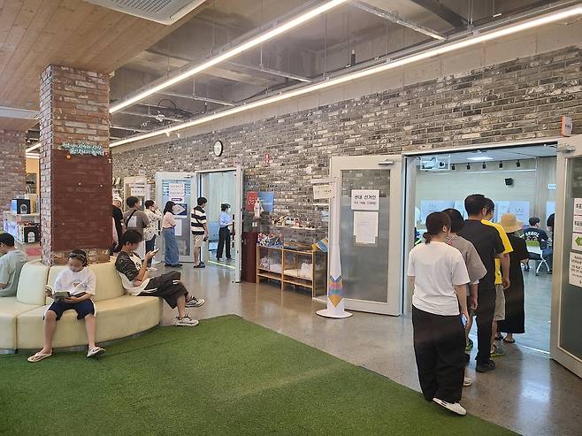 투표소 옆에서 책 읽는 어린이  30일 오후 울산시 남구 옥동 사전투표소가 차려진 청소년차오름센터에서는 미니 도서관에서 책을 읽는 어린이 옆으로 유권자들이 투표를 위해 줄지어 서는 풍경이 연출됐다.[촬영 허광무]