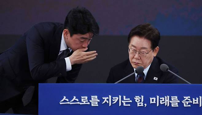 이재명 대통령이 26일 경남 창원시 진해구에서 열린 제1회 미래국방전략위원회에서 강훈식 비서실장과 대화하고 있다. [청와대사진기자단]
