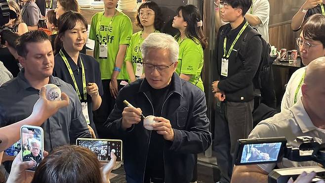 젠슨 황 엔비디아 CEO(가운데)가 1일 오후 대만 타이베이 현지 식당에서 열린 국내 주요 기업 관계자들과의 만찬 자리 '코리안 파트너 나잇'에 참석해 한 시민이 건넨 공에 사인하고 있다. 사진=공동취재단
