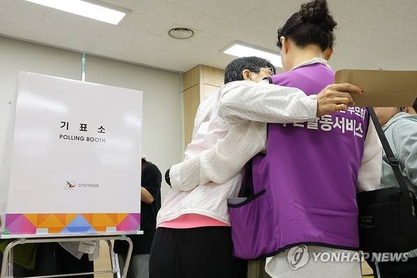 제9회 전국동시지방선거 사전투표 첫날인 29일 한 장애인이 활동보조를 받아 투표에 나서고 있다. /연합뉴스