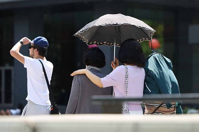 서울 종로구 광화문광장에서 시민이 양산을 쓰고 이동하고 있다. 뉴시스