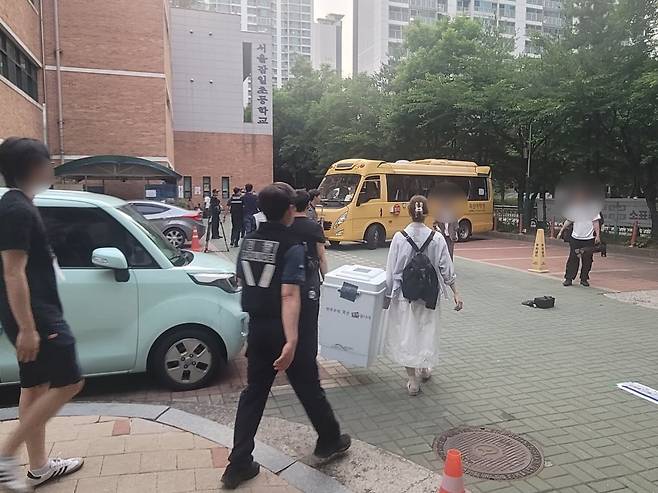 투표용지 부족으로 투표가 일시 중단됐던 서울 송파구 잠실2동 잠일초등학교 제6투표소에서 관계자들이 추가 공급된 투표용지로 투표를 재개한 뒤 투표함을 수거하고 있다. / 임민규 기자