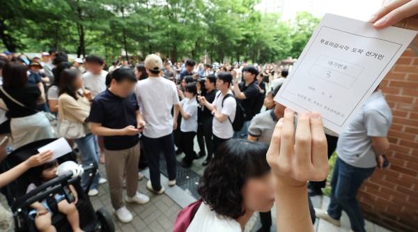 ▲2026년 6월 3일 6·3 지방선거 본투표일에 서울 송파구 잠실2동 6투표소에서 투표용지 부족으로 대기하던 한 유권자가 마감시간 후 대기번호표를 들어 보이고 있다. ⓒ연합뉴스