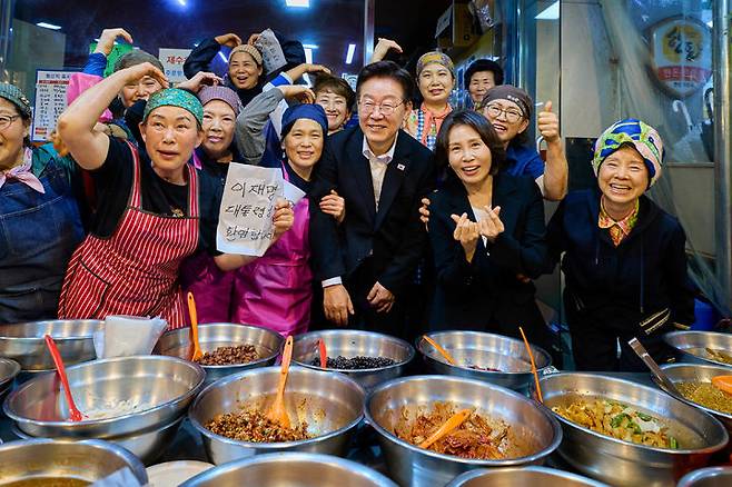 [서울=뉴시스] 최동준 기자 = 이재명 대통령과 김혜경 여사가 23일 경남 김해시 외동전통시장을 방문해 상인들과 기념촬영을 하고 있다. (사진=청와대 제공) 2026.05.23. photo@newsis.com *재판매 및 DB 금지