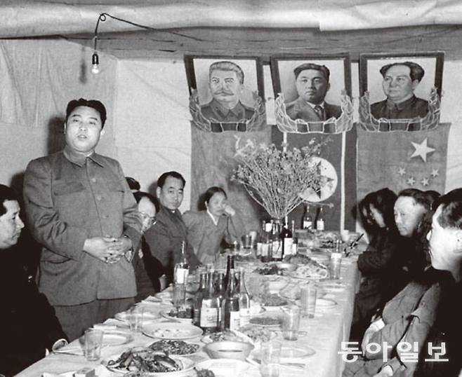1951년 4월, 중국 간부들을 만난 김일성. 천막에 건 김일성 사진 좌우로 스탈린과 마오쩌둥의 사진이 붙어 있다. 동아일보 DB