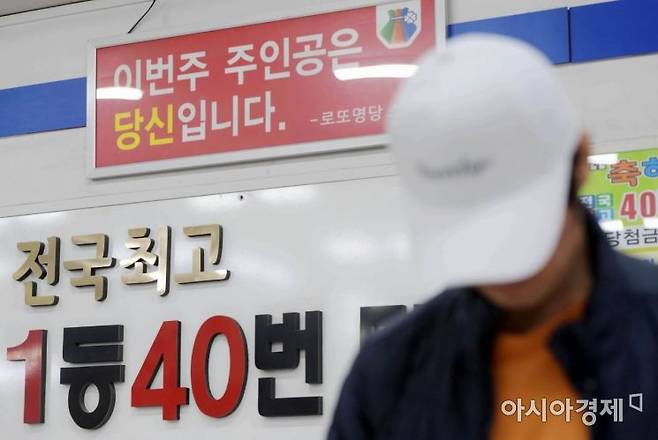 로또 숫자를 조합하고 있는 한 시민의 어깨 너머로 '이번주 주인공은 당신입니다' 문구가 보이고 있다. 문호남 기자