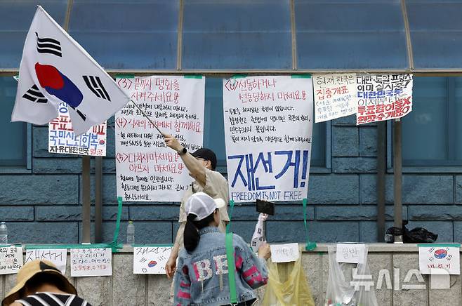 [서울=뉴시스] 김혜진 기자 = 제9회 전국동시지방선거 투표용지 부족 사태에 항의하며 개표소 봉쇄 시위를 이어가는 시민들이 8일 서울 송파구 올림픽공원 핸드볼경기장에 설치된 개표소 앞에서 재선거를 요구하고 있다. 2026.06.08. jini@newsis.com