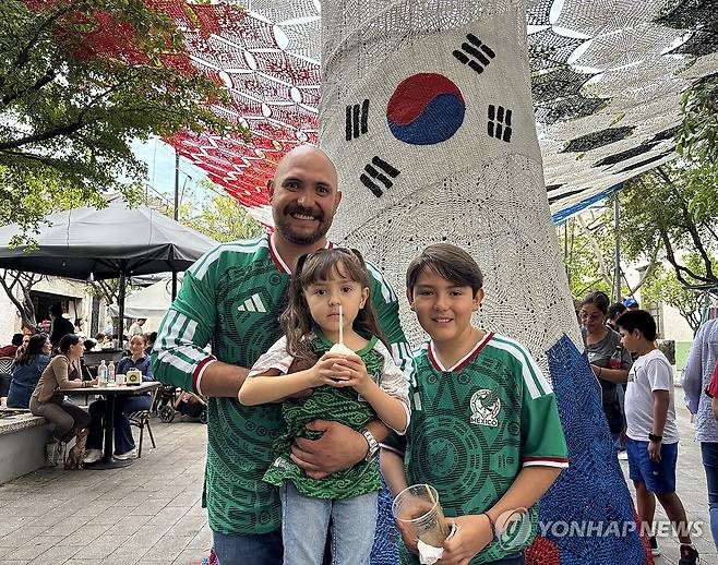 주말 나들이 나온 카를로스 아얄라씨와 두 자녀 (사포판[멕시코 할리스코주]=연합뉴스) 오명언 기자 = 2026북중미 월드컵이 열리는 멕시코 과달라하라 인근 사포판 역사 지구에 있는 보행자 전용 거리에 이지역에서 경기를 치르는 국가를 상징하는 조형물이 설치되어 있다. 7일(현지시간) 축구유니폼을 입은 시민 등이 한국상징 조형물 아래서 기념사진을 찍고 있다. 2026.6.8 coup@yna.co.kr