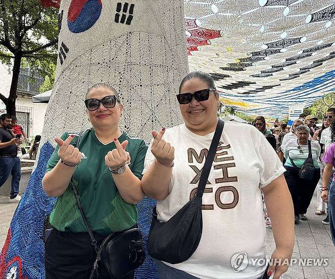태극기 조형물 아래서 손 하트 포즈 짓는 아드리아나 케레로씨(좌측) (사포판[멕시코 할리스코주]=연합뉴스) 오명언 기자 = 2026북중미 월드컵이 열리는 멕시코 과달라하라 인근 사포판 역사 지구에 있는 보행자 전용 거리에 이지역에서 경기를 치르는 국가를 상징하는 조형물이 설치되어 있다. 7일(현지시간) 축구유니폼을 입은 시민 등이 한국상징 조형물 아래서 기념사진을 찍고 있다. 2026.6.8 coup@yna.co.kr