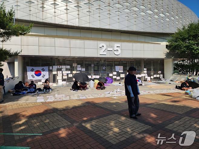 9일 서울시 송파구 올림픽공원 핸드볼경기장의 한 출구 앞에 재선거를 요구하는 시위자들이 돗자리를 펴고 앉아 있다. 이들은 내부에 있는 투표함 반출을 막기 위해 밤샘 농성 중이다. 2026.06.09/ⓒ 뉴스1 권진영 기자