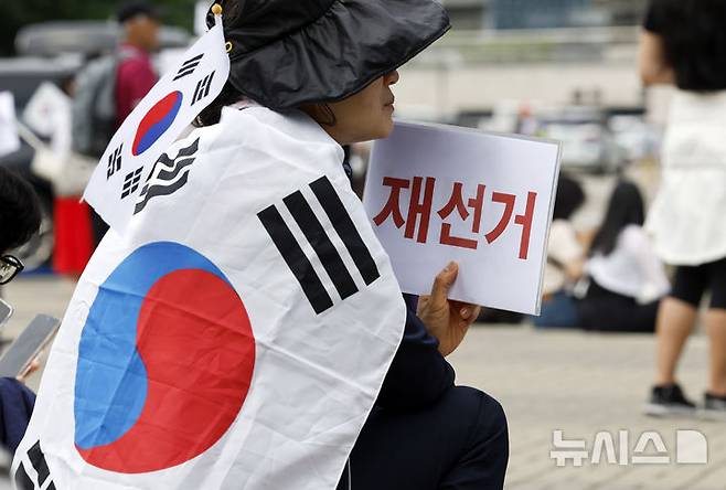 [서울=뉴시스] 김혜진 기자 = 제9회 전국동시지방선거 투표용지 부족 사태에 항의하며 개표소 봉쇄 시위를 이어가는 시민들이 8일 서울 송파구 올림픽공원 핸드볼경기장에 설치된 개표소 앞에서 재선거를 요구하고 있다. 2026.06.08. jini@newsis.com