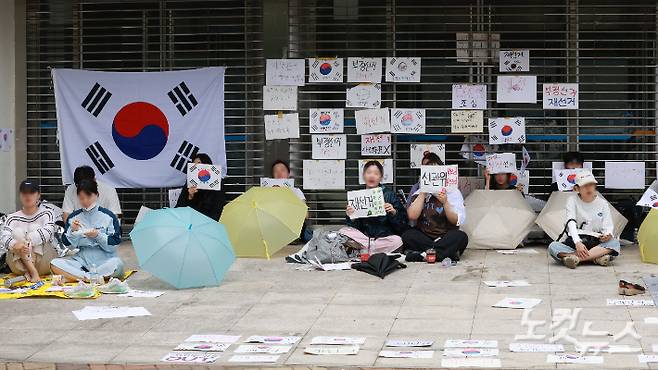6·3 지방선거 투표용지 부족 사태를 규탄하고 재선거를 요구하는 '잠실 개표소 봉쇄 시위'가 나흘째 이어지고 있는 8일 서울 송파구 올림픽공원 핸드볼경기장 출입구 앞에서 시위 참가자들이 구호를 외치고 있다. 류영주 기자