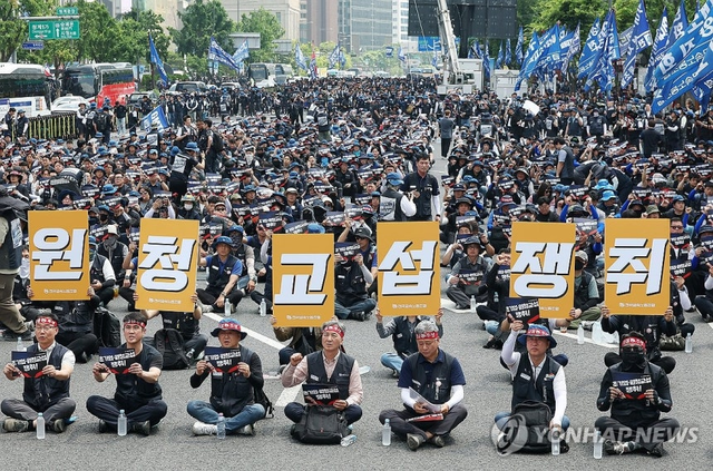 전국금속노동조합(금속노조) 조합원들이 10일 서울 종로구 광화문광장 인근에서 열린 결의대회에서 손팻말을 들고 있다. 연합뉴스