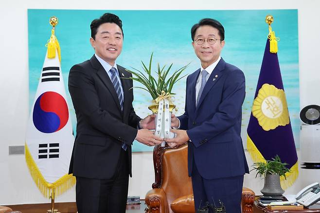 OOO 국회의장(오른쪽)이 9일 취임 축하 인사차 예방한 강훈식 대통령 비서실장에게서 이재명 대통령이 보낸 축하 난을 받고 있다. 연합뉴스