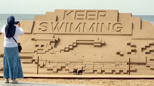 9일 부산 해운대해수욕장을 찾은 관광객이 방탄소년단(BTS) 신곡 ‘KEEP SWIMMING‘이 적힌 대형 모래 작품을 사진 촬영하고 있다. 연합뉴스
