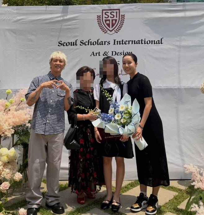 Singer and performance artist Poppin Hyun-joon has shared a photo taken with actor Jang Dong-gun and his wife Ko So-young, whom he happened to run into at his daughters middle school graduation ceremony. Poppin Hyun-joon took to social media to celebrate his daughters graduation and share a heartwarming snapshot of his family together.In the released photo, Poppin Hyun-joon and the couple Jang Dong-gun and Ko So-young are seen looking affectionately at the camera. Poppin Hyun-joon expressed his love for his daughter, who has grown up well without any teenage troubles, and added a message congratulating her on her graduation.Meanwhile, the international school attended by Poppin Hyun-joons daughter has drawn public attention as its annual tuition is reported to be around 25 million won. Poppin Hyun-joon married traditional Korean musician Park Ae-ri in 2011, and they have a daughter named Yeol-seul.