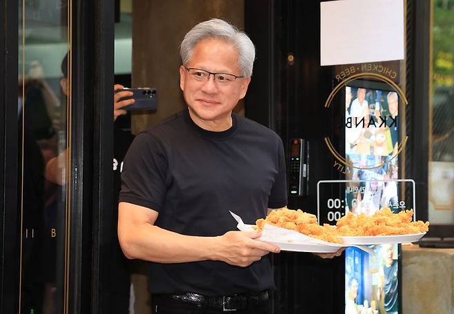 젠슨 황 엔비디아 최고경영자(CEO)가 지난 7일 오후 서울 강남구 깐부치킨 삼성점에서 최태원 SK그룹 회장과 '치맥 회동' 중 시민 및 취재진에게 치킨을 나눠주고 있다. 2 뉴스1