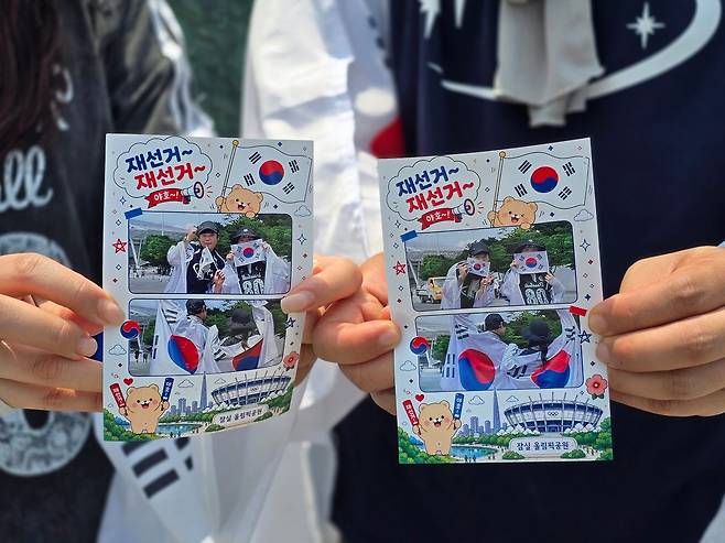 14일 서울 송파구 잠실 올림픽공원 핸드볼경기장 인근에 청년 사업가 장모(32)씨가 준비한 즉석사진 ‘올공두컷’ 부스에서 2030 집회 참가자들이 촬영한 사진을 손에 들고 있다. 손성배 기자