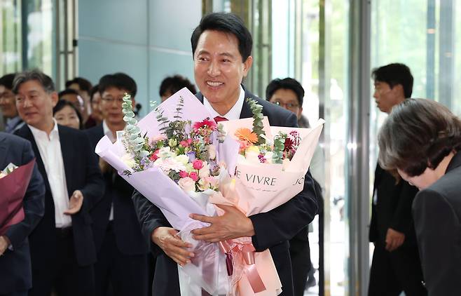 오세훈 서울시장이 4일 서울시청 로비에서 당선 축하 꽃다발을 받은 뒤 기뻐하고 있다. [연합]