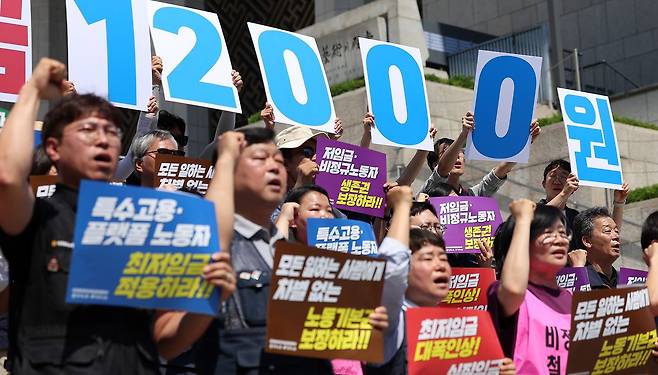 한국노총과 민주노총 관계자들이 15일 서울 종로구 세종문화회관 앞 계단에서 열린 2027년 적용 최저임금 노동계 요구안 발표 기자회견에서 구호를 외치고 있다. 뉴스1