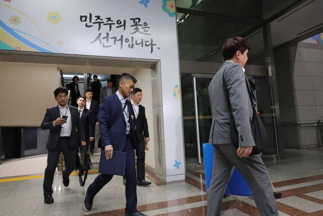 6·3 전국동시지방선거 투표용지 부족 사태를 들여다보고 있는 검경 합동수사본부 관계자들이 11일 경기도 과천 중앙선거관리위원회에서 압수수색을 마친 뒤 압수품을 들고 건물을 나서고 있다. 연합뉴스