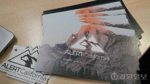 ◇UC 샌디에이고 ALERTCalifornia 연구실에 놓인 홍보용 엽서와 로고 스티커. ALERTCalifornia는 “Always live at alertcalifornia.org”라는 문구처럼 일반 시민도 공개 사이트를 통해 캘리포니아 전역의 산불 감시 카메라 영상을 실시간으로 확인할 수 있도록 운영된다. 미국 샌디에이고=김태훈 기자