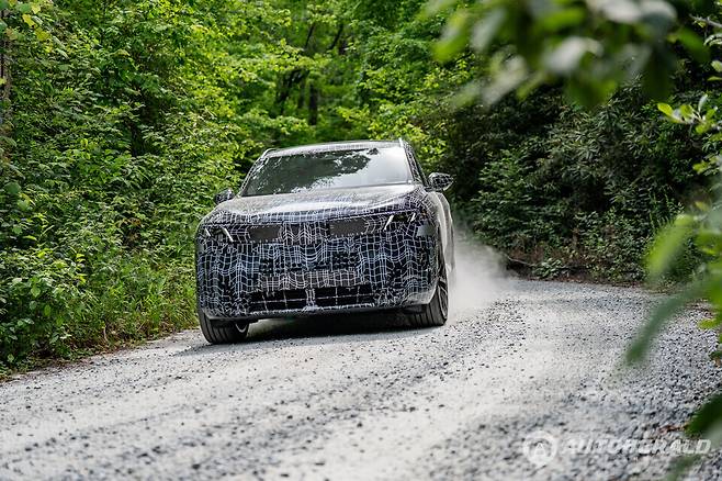 위장막을 두른 차세대 BMW X5가 비포장 테스트 코스를 달리며 최종 주행 성능 검증을 진행하고 있다. 신형 X5는 전기차와 수소연료전지 모델을 포함한 다양한 파워트레인 라인업으로 출시될 예정이다. (BMW)