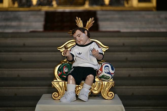 멕시코 축구대표팀 유니폼을 입은 아기 예수상이 16일 멕시코시티 대성당 알타르 데 로스 레예스에 전시돼 있다. 2026 북중미 월드컵에서 멕시코 대표팀의 선전을 기원하는 시민들이 이곳을 찾아 소원을 빌고 있다. AFP