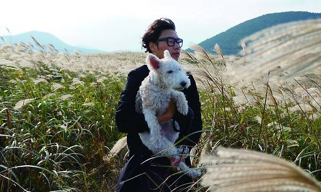 2000년대 초부터 ‘올드독’ 캐릭터로 시사만화, 웹툰을 그려온 만화가 정우열 작가가 3년 전 떠난 반려견 ‘풋코’를 안고 있다. 그는 나이 든 반려견과의 생활을 만화 ‘노견일기’에 담아왔는데, 최근 책이 13권으로 완간됐다. 정우열 작가 제공