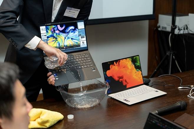 에이수스(ASUS) 관계자가 자사 노트북의 내구성 검증을 위해 자판에 물을 붓는 모습. 에이수스