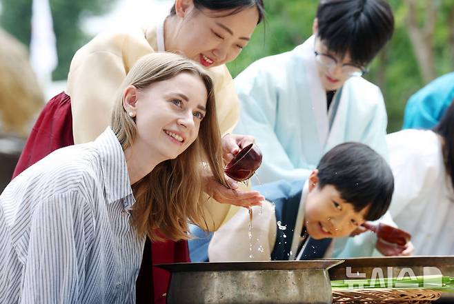 [서울=뉴시스] 김진아 기자 = 단오(6월 19일)를 앞두고 17일 서울 종로구 국립민속박물관 오촌댁 앞마당에서 열린 '단오 세시' 행사에서 외국인과 어린이가 창포물에 머리감기 체험을 하고 있다. 22026.06.17. bluesoda@newsis.com
