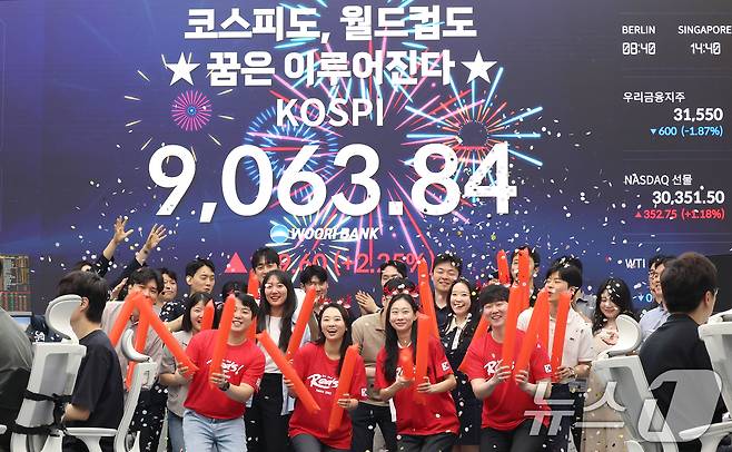 코스피 지수가 전인미답의 9000선 고지를 돌파한 18일 오후 서울 중구 우리은행 본점 딜링룸에서 직원들이 코스피 종가를 배경으로 축하 세리머니를 하고 있다.  ⓒ 뉴스1 오대일 기자