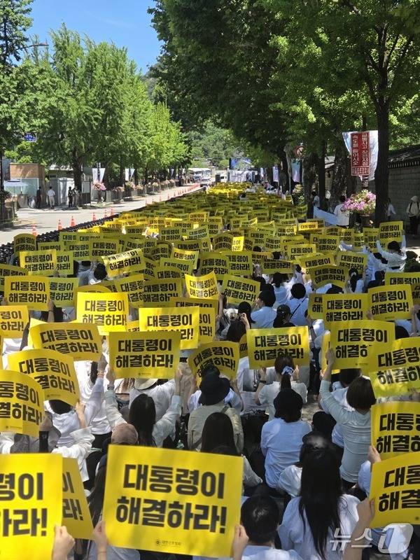 대한간호협회 소속 간호사들이 23일 서울 종로구 청와대 분수대 인근에서 열린 '진료지원 간호사 교육체계 정상화 촉구 대회'에 참석해 "대통령이 해결하라"는 손팻말을 들고 정부의 교육체계 이원화 방침 철회를 요구하고 있다. (대한간호협회 제공)