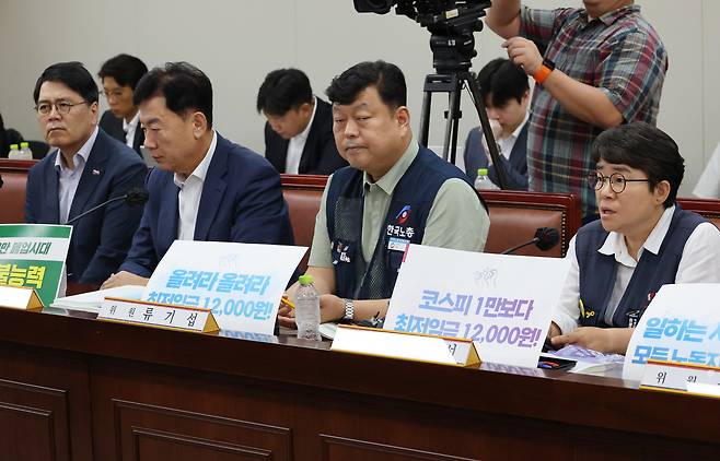 23일 정부세종청사 최저임금위원회에서 열린 제8차 전원회의에서 근로자위원인 이미선 민주노총 부위원장이 “코스피 1만보다 최저임금 12,000원!” 이라고 적은 피켓을 세워두고서 발언하고 있다. 연합뉴스