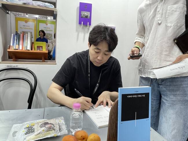 고명재 시인이 ‘어깨를 머리에 기대던 시절’ 시집에 사인을 해주고 있다.