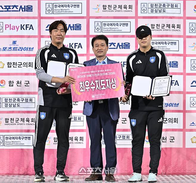 울산 현대고(여) 안연진 감독과 신재환 코치가 26일 합천 군민체육공원에서 열린 ‘2026 스포츠케이션 명품도시 합천에서 펼쳐지는 제34회 여왕기 전국여자축구대회’ 고등부 시상식에서 최우수지도자상을 수상한 후 울산현대고 김태형 교장과 포즈를 취하고 있다.  2026. 6. 26. 합천 | 최승섭기자 thunder@sportsseoul.com