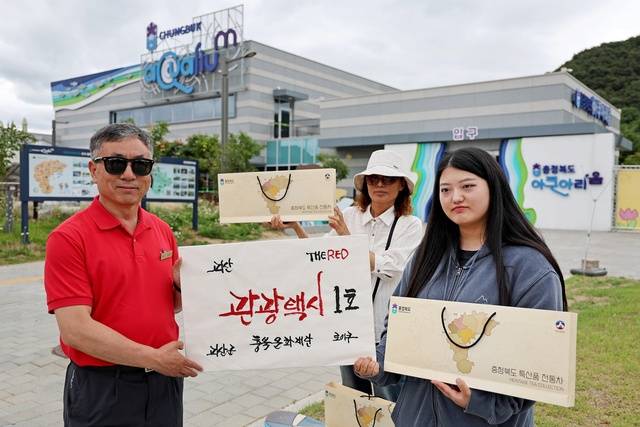 ▲ 괴산군 맞춤형 관광택시 1호 기사인 이승수씨(왼쪽)가 관광객들과 기념촬영하고 있다. /괴산군 제공