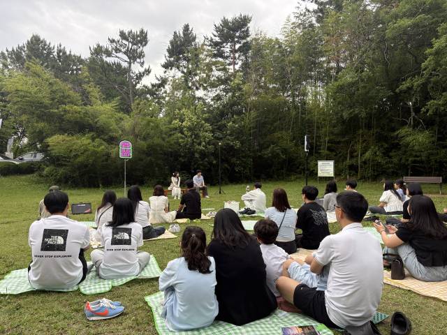 지난 21일 오후 경남 도민의 집 인근 잔디밭에서 관객들이 창원시민뮤지컬단의 버스킹형 뮤지컬 ‘버스정류장’을 관람하고 있다.