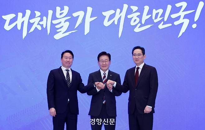 이재명 대통령이 29일 청와대에서 열린 ‘대한민국 대도약 3대 메가프로젝트 국민보고회’에서 최태원 에스케이(SK)그룹 회장과 이재용 삼성전자 회장과 함께 손을 맞잡고 있다. 청와대사진기자단