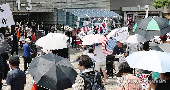 더위 속 봉쇄 시위 계속 (서울=연합뉴스) 이진욱 기자 = 6·3 지방선거 당시 잠실 개표소로 사용된 서울 송파구 올림픽공원 핸드볼경기장 앞에서 28일 투표용지 부족 사태 규탄 봉쇄 시위 참가자들이 우산을 쓰고 구호를 외치고 있다. 2026.6.28 cityboy@yna.co.kr