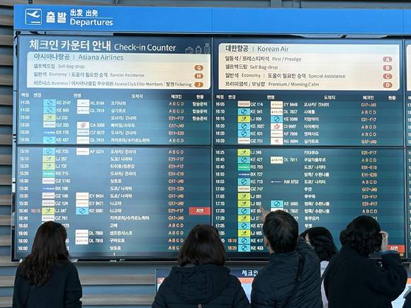 아시아나항공의 인천공항 제2터미널 이전 이후 첫 주말인 17일, 출국객들이 체크인 카운터 인근에서 안내 전광판을 확인하고 있다. [사진=권서아 기자]