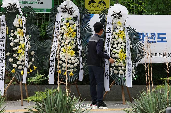 한 시민이 쓰러진 근조화환을 바로 세워 정리하고 있다.