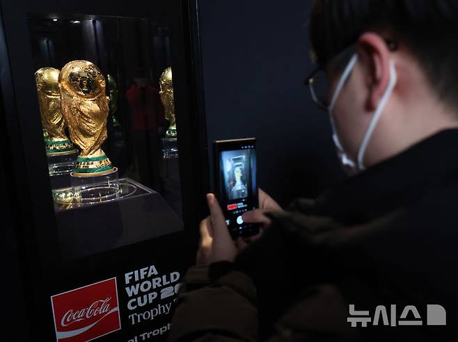 [서울=뉴시스] 배훈식 기자 = 코카-콜라 '오리지널 FIFA 월드컵™ 트로피'가 일반에 공개된 17일 오전 서울 용산구 CGV 용산아이파크몰을 찾은 시민이 공식 트로피 사진을 찍고 있다. 2026.01.17. dahora83@newsis.com
