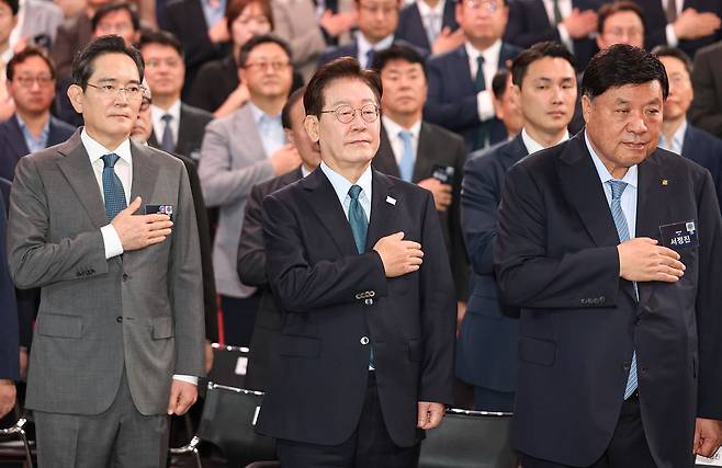 이재명 대통령이 2일 충남 아산시에서 열린 충청권 첨단산업 발전비전 국민보고회에서 국민의례를 하고 있다.   왼쪽부터 이재용 삼성전자 회장, 이재명 대통령, 서정진 셀트리온 회장. 연합뉴스