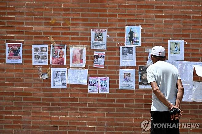 1일(현지시간) 베네수엘라 라과이라주에서 한 남성이 벽에 붙은 실종자들의 사진을 보고 있다. [AFP=연합뉴스]