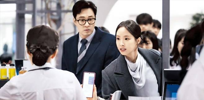 지난달 26일 방송된 SBS 드라마 ‘김부장’에서 딸 생일 선물을 고르기 위해 백화점을 찾은 김 부장(소지섭)이 예약 확인을 못해 미리 골라 놓은 제품을 찾지 못할 뻔했으나, 회사 부하 직원 정상아(손나은)가 나타나 스마트폰 예약 내역을 보여주며 물건을 찾고 있다. /SBS