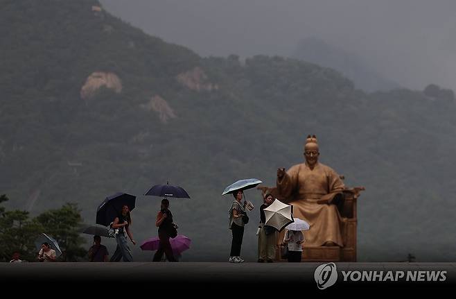 장마 (서울=연합뉴스) 신준희 기자 = 6일 서울 광화문광장에 드리워진 비구름떼 아래 우산을 든 시민들이 걸어가고 있다. 2026.7.6 hama@yna.co.kr