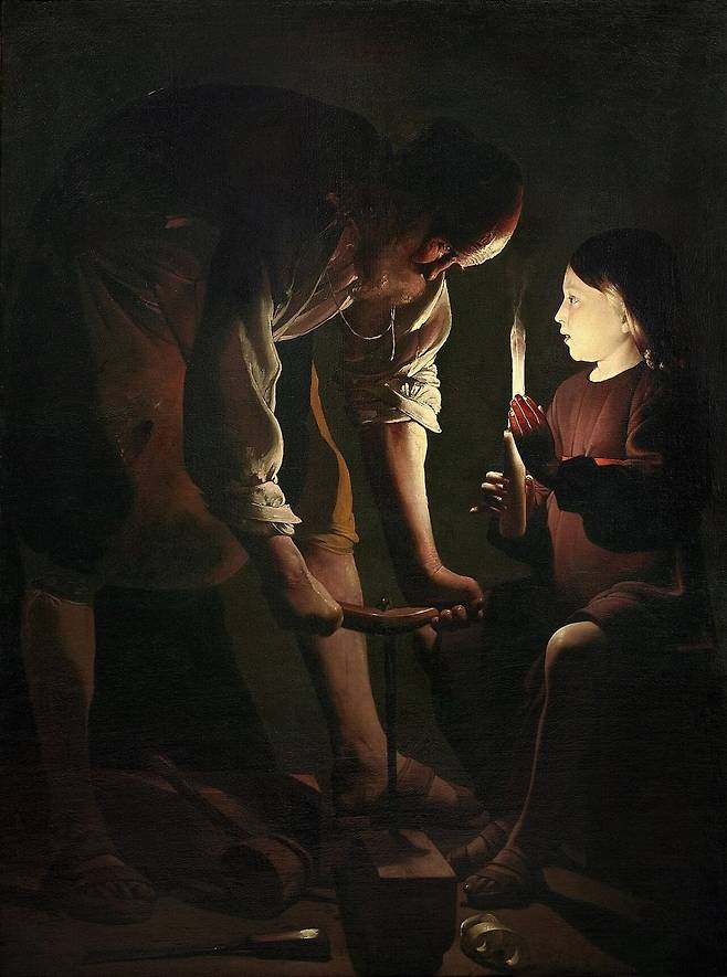 목수 성 요셉(1642~44경). 노인이 뚫는 건 평범한 나무 구멍이지만, 그가 쥔 송곳이 이루는 십자 모양은 훗날 예수가 못 박힐 십자가를 미리 비춘다고 읽힌다. 그림을 밝히는 빛이 오직 어린 예수가 든 촛불 하나뿐이라, 늙은 아버지를 어린 자식이 비추는 이 구도에 여러 신학적 해석이 따라붙는다. /파리 루브르 박물관