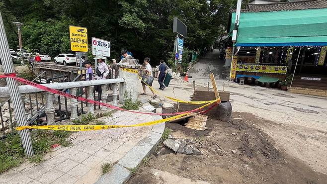 11일 오전 10시 충남 공주시 반포면 계룡산 동학사 입구에 지난 9일 내린 폭우로 파인 도로에 임시 경계선이 설치돼 있다. 신진호 기자