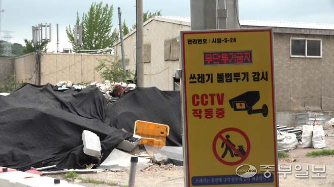 쓰레기 불법투기 CCTV 감시 안내판 뒤로 각 종 쓰레기들이 검은천에 덮여 있다. 배상일 기자